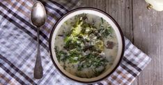 a bowl of soup with broccoli and cheese on a checkered table cloth