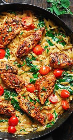 pasta with chicken, tomatoes and spinach in a skillet on a wooden table