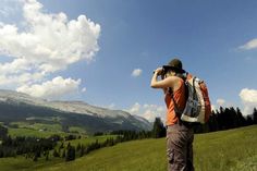 a man with a backpack is looking into the distance while standing on a hill side