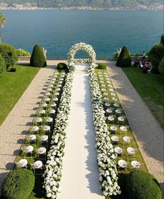 an outdoor wedding setup with white flowers and greenery on the side of the aisle