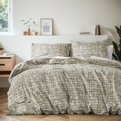 a bed in a room with wooden floors and a plant on the side of the bed