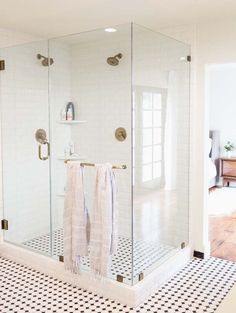 a bathroom with black and white tile flooring and a glass shower door that is open