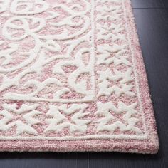 a pink and white rug on the floor with an intricate design in the middle,