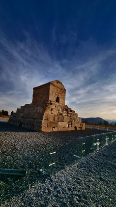 a stone structure sitting on top of a gravel field