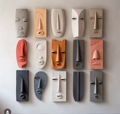 several different colored masks are arranged on a white wall, each with their own face