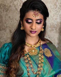 a woman in a green and blue outfit with gold jewelry