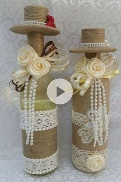 two bottles decorated with lace, pearls and flowers are sitting side by side on a white background