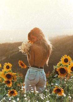 a woman standing in a field of sunflowers with her back to the camera