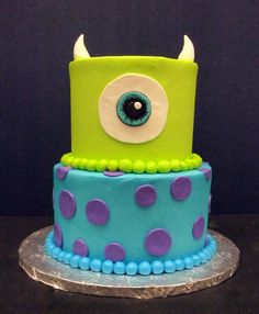 a blue and green birthday cake with monster eyes on it's top tiers