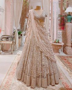 a wedding dress on display in a room with white curtains and pink carpeted flooring