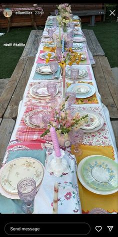 a long table with plates and flowers on it is set for an outdoor dinner party