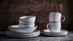 a stack of white cups and saucers sitting next to each other on a table