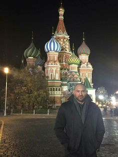 a man standing in front of a building with domes on it's sides at night