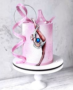 a pink and white cake with a figure painted on the side, sitting on top of a pedestal