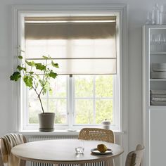 a white table and chairs in front of a window with blinds on the windowsill