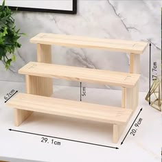 three tiered wooden shelf with measurements for the top and bottom shelves, on a marble countertop