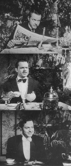 two men in tuxedos are sitting at a table and one man is reading