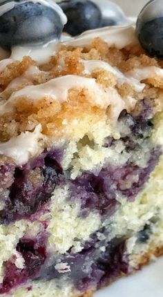 a close up of a piece of cake with blueberries and cream frosting on it