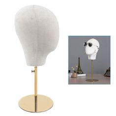 a white mannequin head sitting on top of a wooden stand next to a lamp