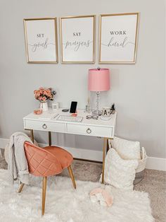 a white desk topped with a pink lamp next to two framed pictures