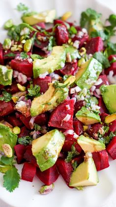 a white plate topped with beets, avocado and cilantro sauce