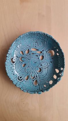 a decorative blue bowl sitting on top of a wooden table with holes in it's center