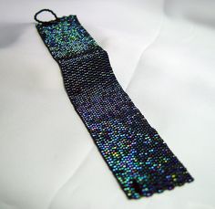 a tie that is laying on top of a white sheet with black and blue sequins