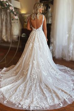 a woman in a wedding dress looking down at the back of her gown, while she is