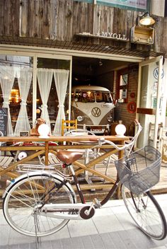 a bicycle parked in front of a building with an old vw bus behind it