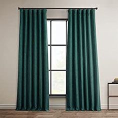 a green curtain hanging on the side of a window in front of a white wall