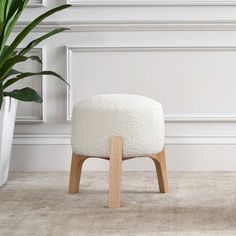 a white stool sitting next to a potted plant on top of a carpeted floor