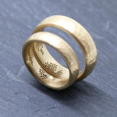 two gold wedding rings with the words love and hope engraved on them, sitting on a blue surface