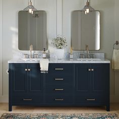 two sinks and mirrors in a bathroom with blue cabinets, rugs and white walls