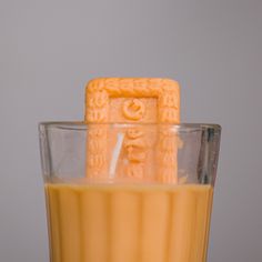 an orange juice in a blender with the lid on it's side, next to a gray background