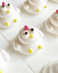 there are many white cupcakes with yellow and pink decorations on them that look like animals