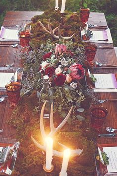 the table is set with candles, flowers and deer antlers for an elegant look