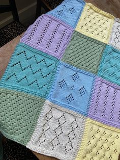 a crocheted blanket sitting on top of a wooden table next to a chair