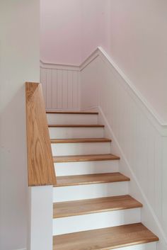 some white and wood stairs in a pink room