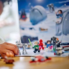 a young boy is playing with legos on the table in front of a star wars poster