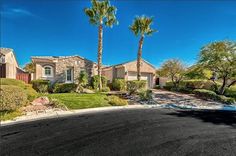 a home with palm trees in the front yard and landscaping on either side of the driveway