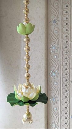 a white and green flower is hanging from a gold chandelier in a room