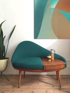 a blue chair sitting in front of a painting on the wall next to a potted plant