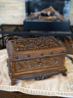 an ornate wooden box sitting on top of a table next to a fireplace in a living room