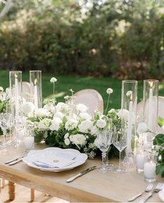 the table is set with white flowers, candles and glass vases for an elegant look