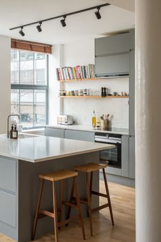 a kitchen with two stools in front of an island and bookshelves on the wall