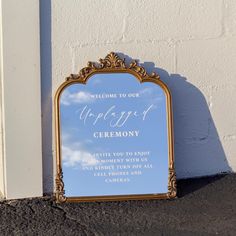 a mirror sitting on the side of a building next to a white wall with a sign that says welcome to our wedding ceremony