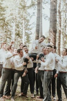 a group of men standing next to each other in front of a forest filled with trees