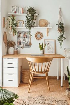 a wooden desk sitting in the middle of a living room next to a plant filled wall