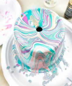 a marbled cake sitting on top of a white plate next to paintbrushes