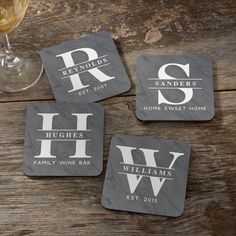 four personalized coasters sitting on top of a wooden table next to a glass of wine